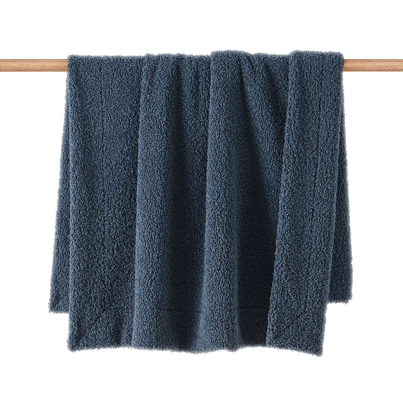 Teddy bear boucle throw blanket in navy blue with plush curled-loop woven texture, draped over a sofa